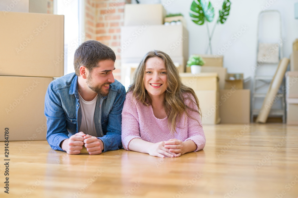 Young beautiful couple in love relaxing lying on the floor together with cardboard boxes around for moving to a new house Young beautiful couple in love relaxing lying on the floor together with cardboard boxes around for moving to a new house