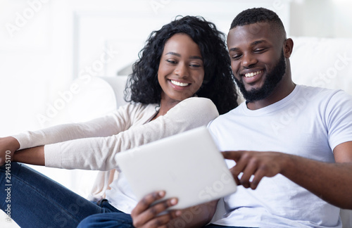 Cheerful african american couple using digital tablet watching funny videos