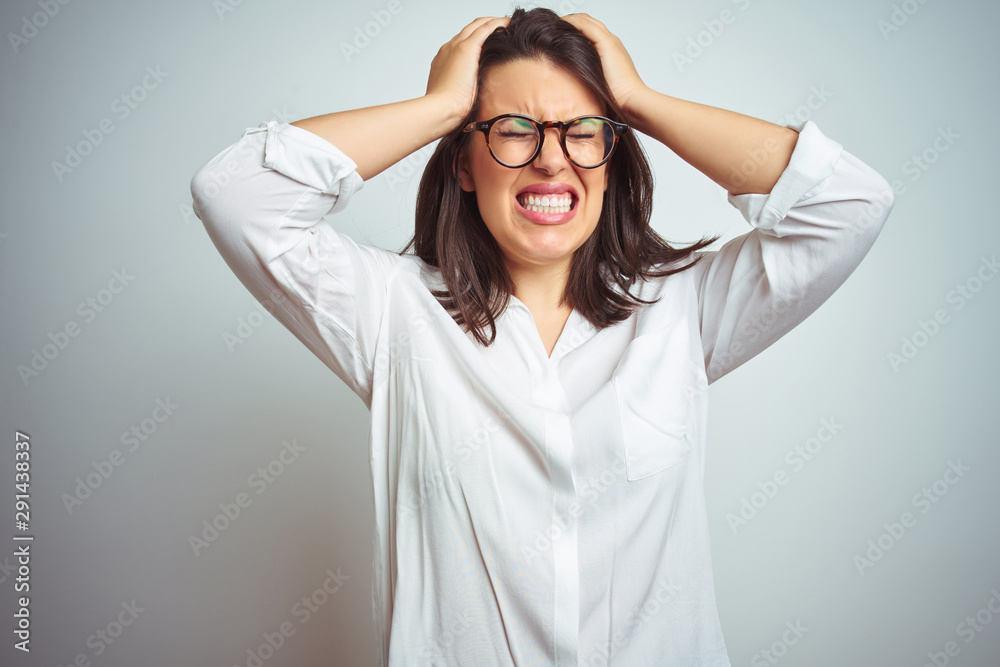 Young beautiful business woman wearing glasses over isolated background suffering from headache desperate and stressed because pain and migraine. Hands on head. Young beautiful business woman wearing glasses over isolated background suffering from headache desperate and stressed because pain and migraine. Hands on head.