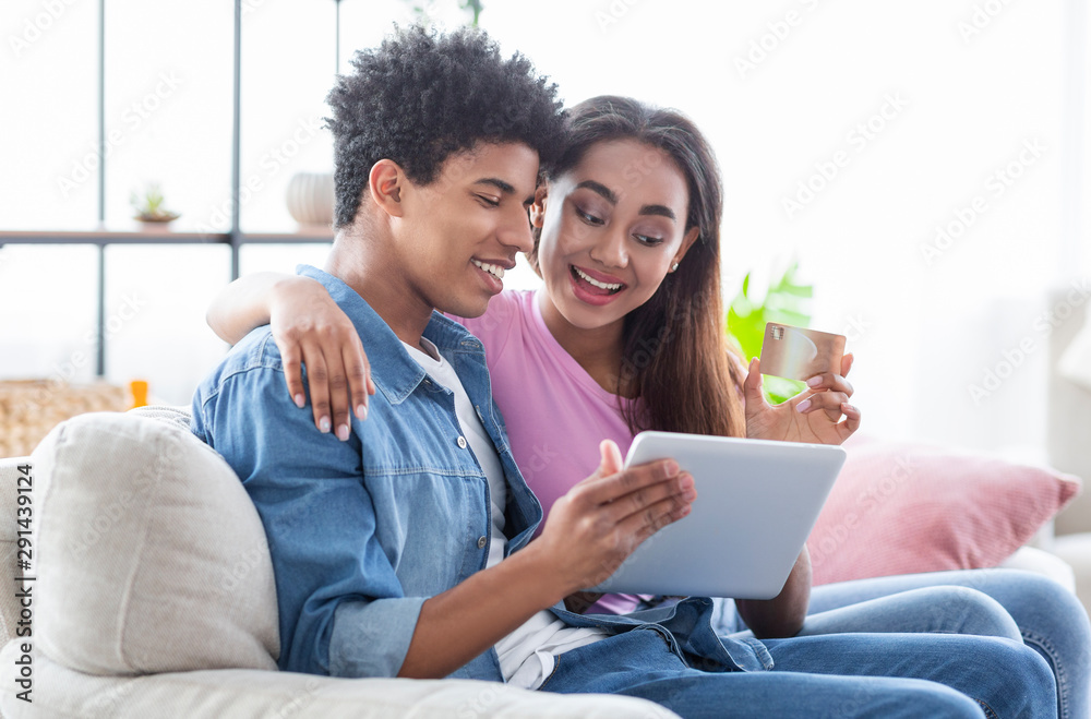 Teenage Couple Shopping Online Using Digital Tablet At Home