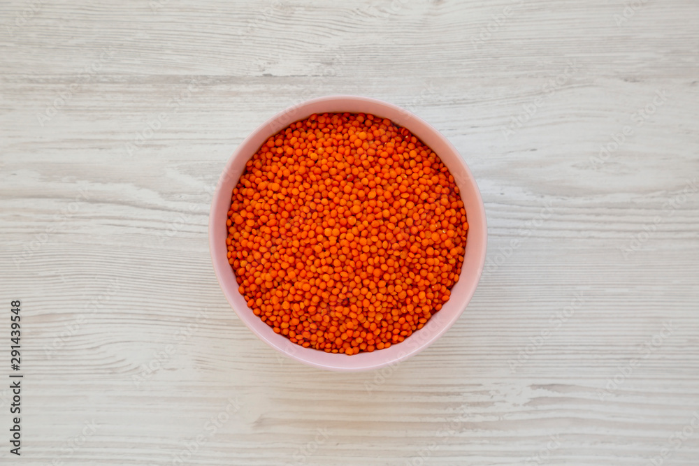 Red lentils in a pink bowl over white wooden background, top view. Flat lay, overhead, from above. Red lentils in a pink bowl over white wooden background, top view. Flat lay, overhead, from above.