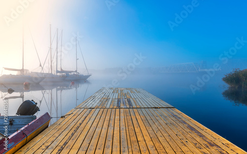 Autumnal mist on a river with yachts and boats anchored in harbor,  at dawn, ...