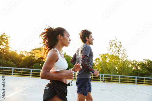 Photo of multinational slim couple running together
