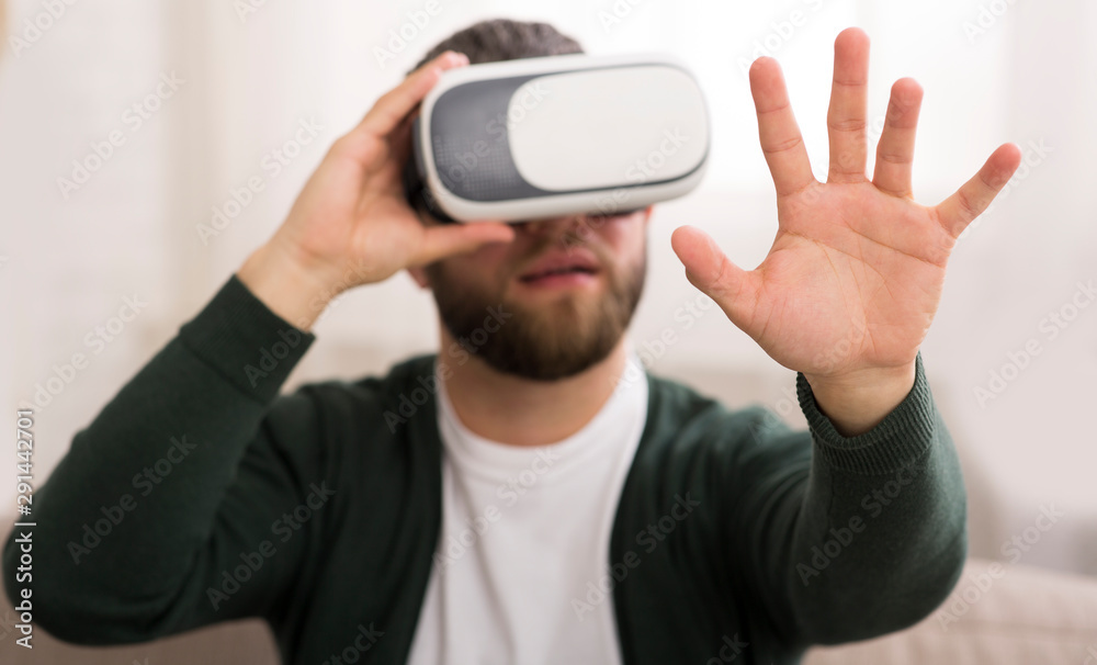 Man using vr glasses at home, looking at his hand Man using vr glasses at home, looking at his hand