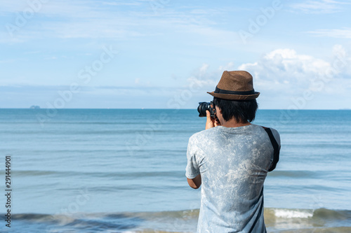 Young men take a photo at the tropical beach. © Pattarisara