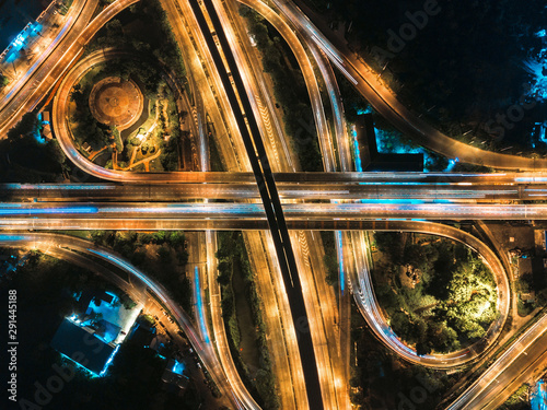Beautiful roundabout intersection at night view. Aerial view of circle transportation in the city with colorful light. Drone view from night sky.