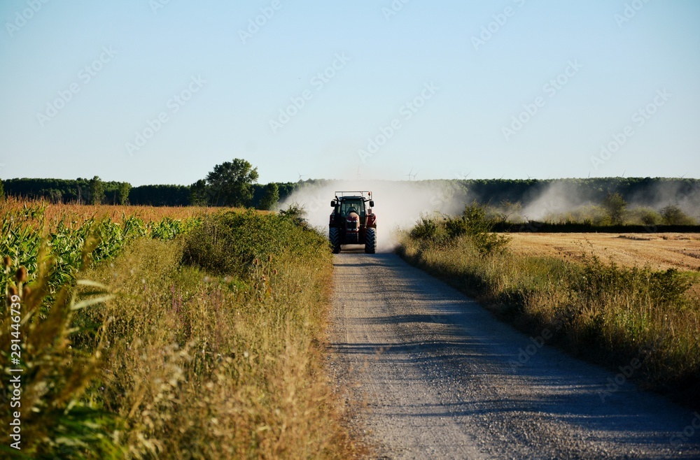 Un tractor por una carretera levantando polvo Un tractor por una carretera levantando polvo