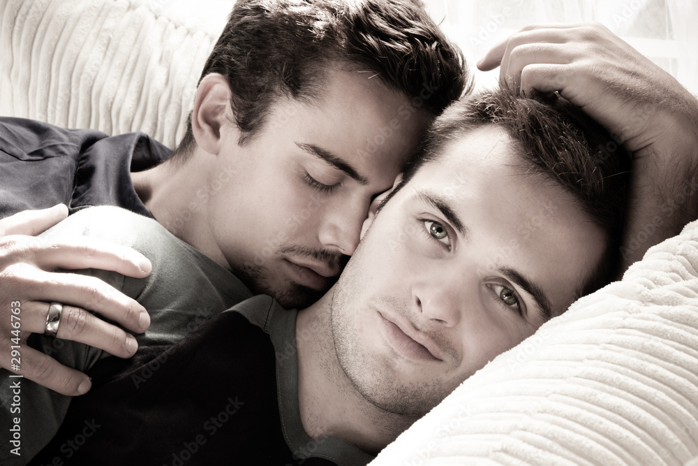 Smiling handsome gay man looks at camera as his partner or husband kisses  his cheek Stock Photo | Adobe Stock