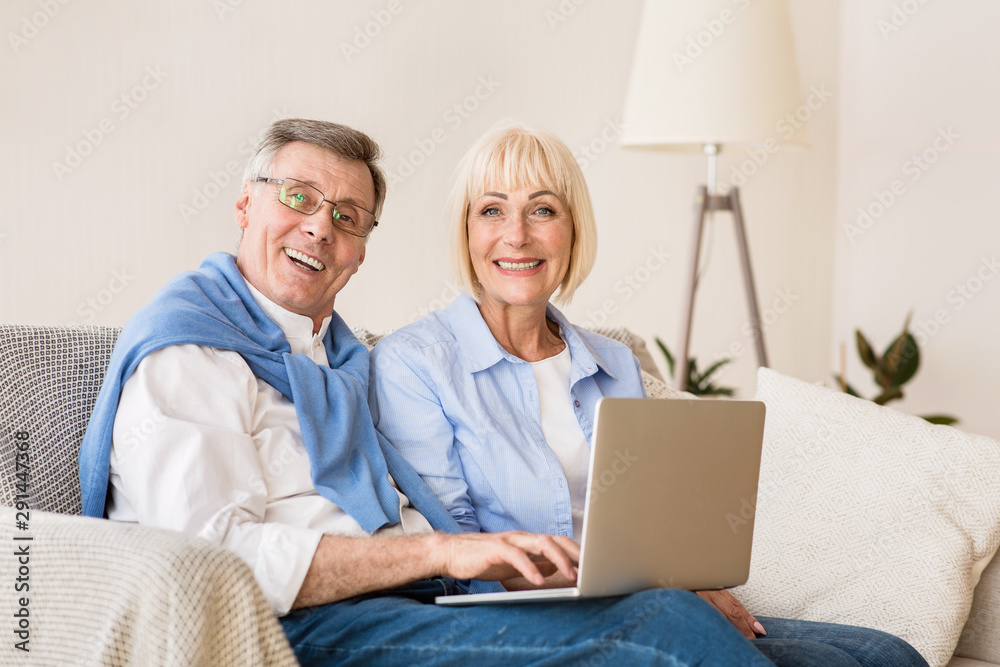 Happy mature couple with laptop computer smiling to camera Happy mature couple with laptop computer smiling to camera