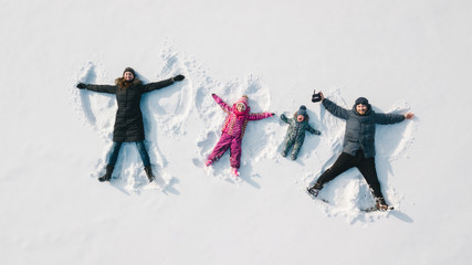 Family making a snow angel. Aerial view. Mother and father and chilren making a snow angel