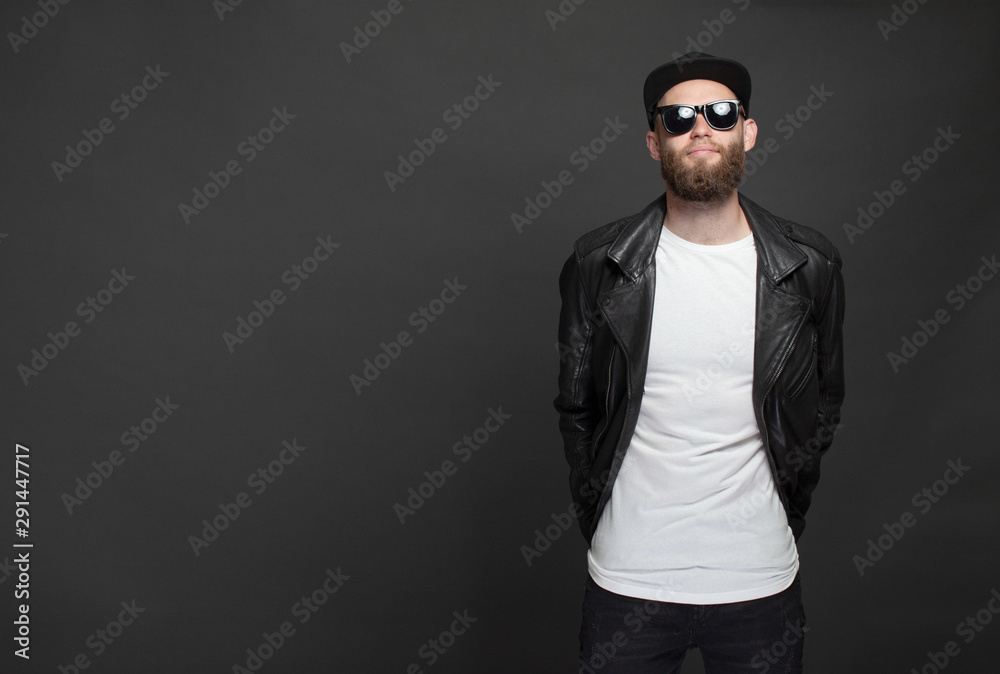 Hipster handsome male model with beard wearing white blank t-shirt and a baseball cap with space for your logo or design in casual urban style