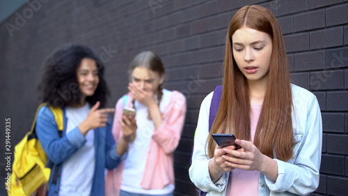 Bullied female student reading embarrassing news social networks by smartphone