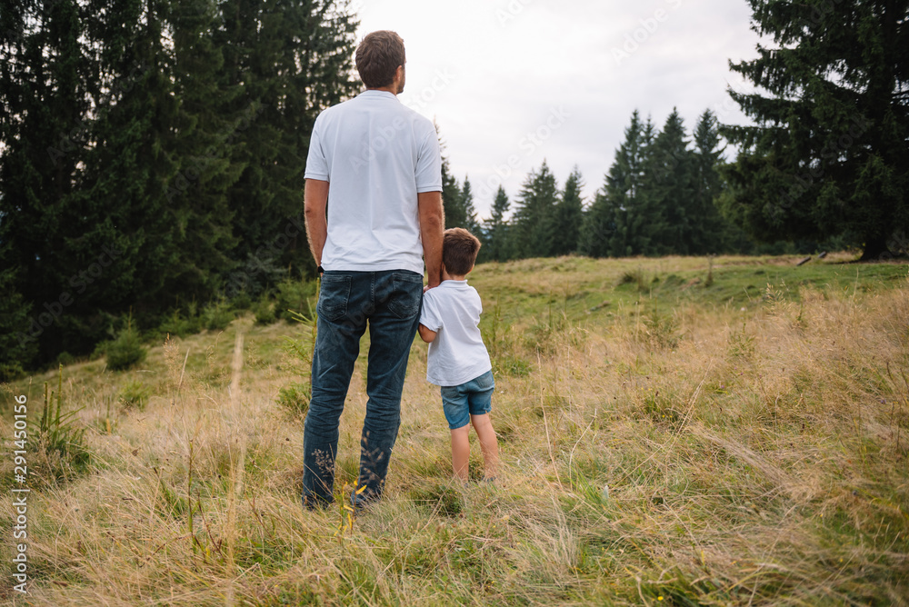 Father and child hiking in scenic mountains. Dad and son enjoying the view from the mountain top in Carpathian mountains Father and child hiking in scenic mountains. Dad and son enjoying the view from the mountain top in Carpathian mountains