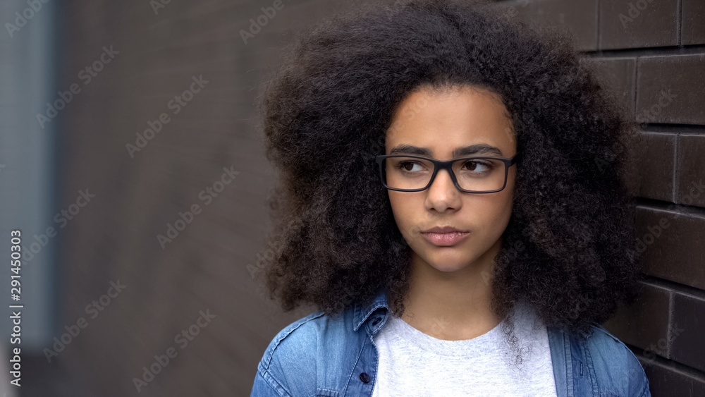 Thoughtful african schoolgirl brick wall background, awkward age insecurities Thoughtful african schoolgirl brick wall background, awkward age insecurities