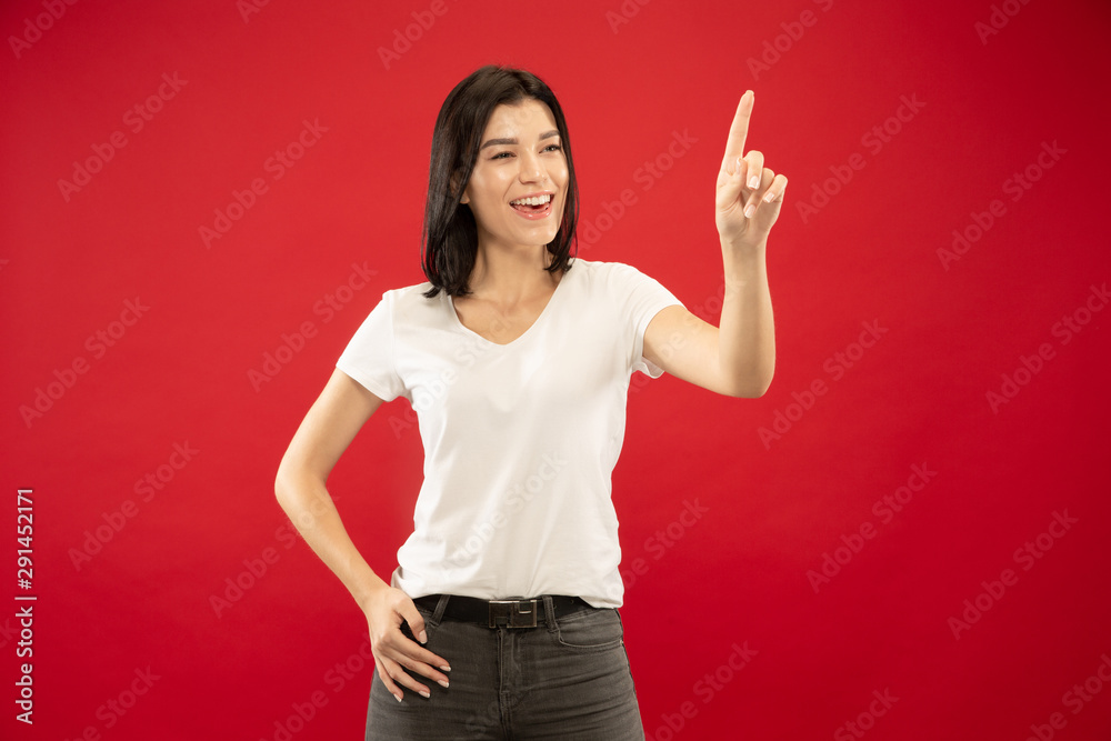 Caucasian young woman's half-length portrait on red studio background. Beautiful female model in white shirt. Concept of human emotions, facial expression. Touching empty search bar, copyspace. Caucasian young woman's half-length portrait on red studio background. Beautiful female model in white shirt. Concept of human emotions, facial expression. Touching empty search bar, copyspace.