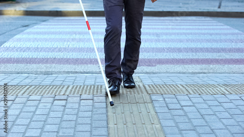Visually impaired man using tactile tiles to navigate city, finishing crossroad