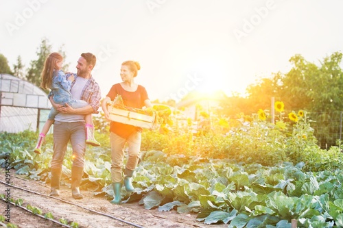 Portrait of a family of famers carrying their vegetables home in wooden boxes, at the end of the day, the Father is carrying their dauaghter photo