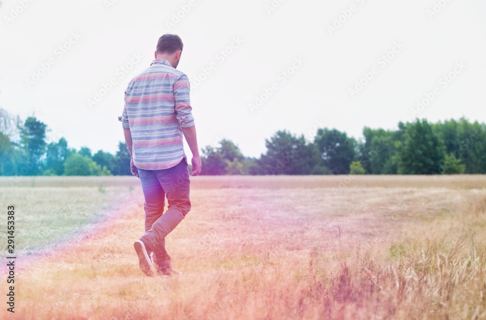 Rear view of Man walking alone in field