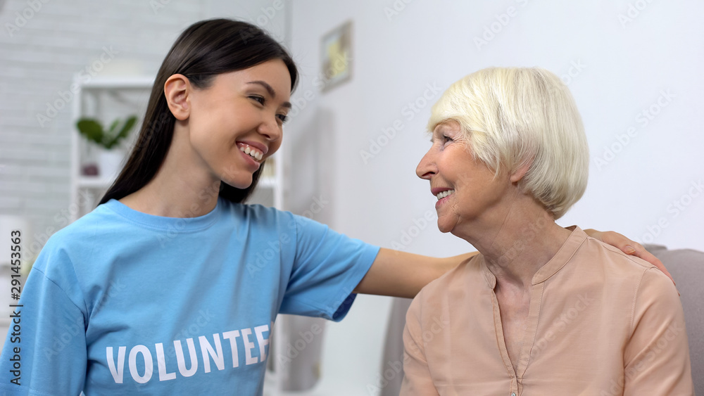 Obraz premium Woman in volunteer T-shirt and senior woman looking at each other, caregiving