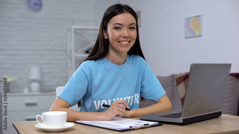 Female volunteer smiling sitting at laptop, financial project of charity fund Female volunteer smiling sitting at laptop, financial project of charity fund