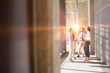 Business people brainstorming in office hall with yellow lens flare in background
