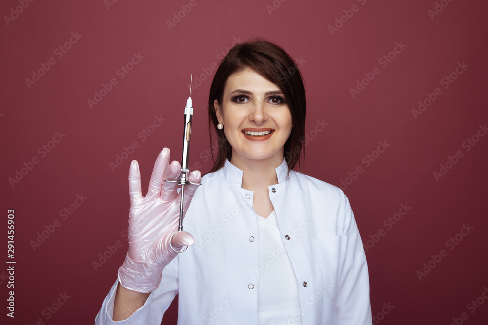 Female dentist holding syringe and smiling isolated over the pink background Female dentist holding syringe and smiling isolated over the pink background
