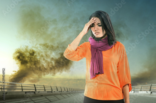 Asian woman getting sick with a headache because of unhealthy air from pollution