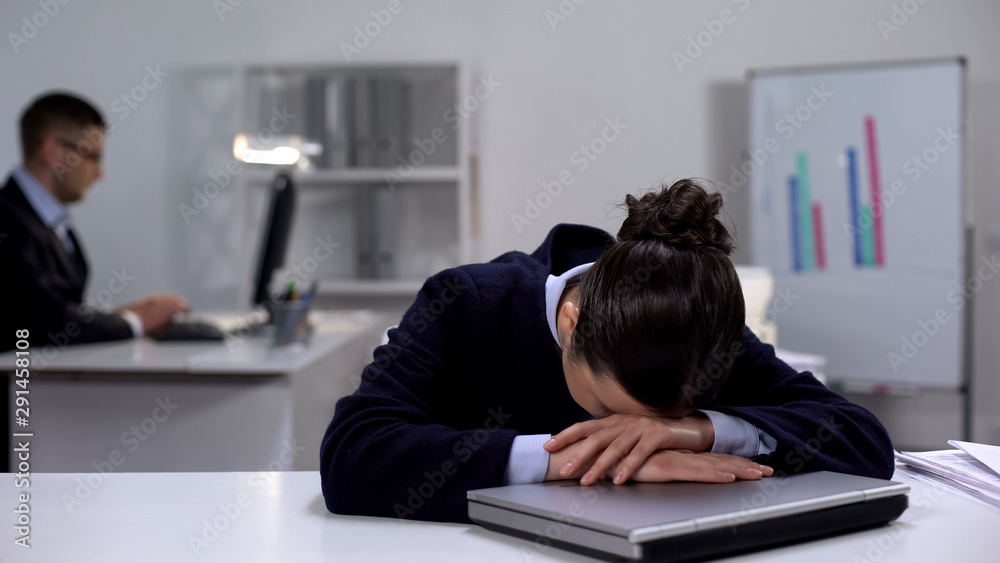 Obraz premium Exhausted female manager lying on laptop, tense working schedule, burnout