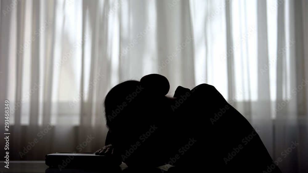 Tired business woman silhouette lying on closed laptop, desperate of overwork