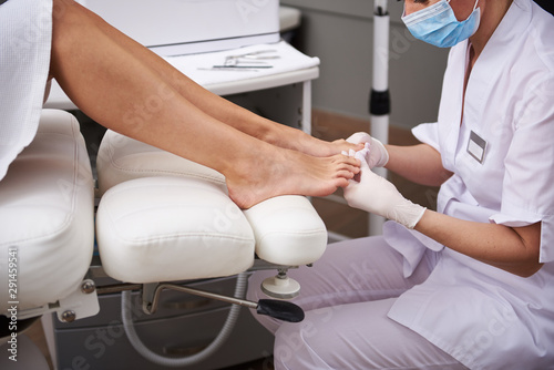 Professional pedicurist checking condition of woman toenails