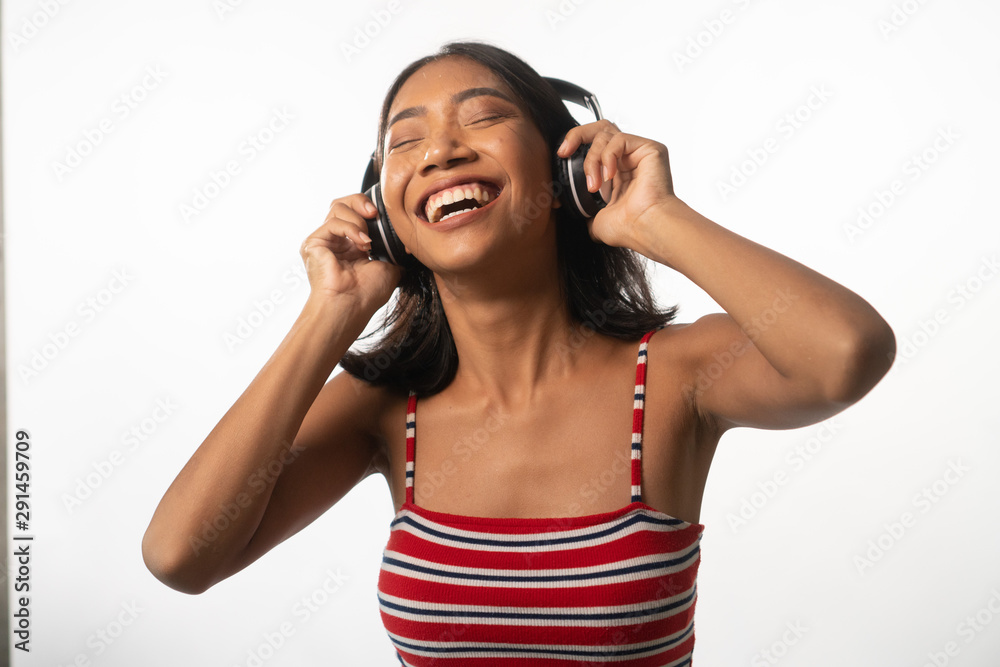 Portrait of happy young Asian girl with headphones dancing over white wall background Portrait of happy young Asian girl with headphones dancing over white wall background