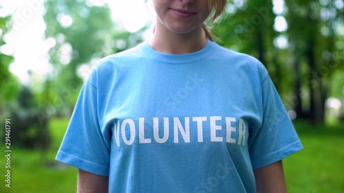 Female in volunteer t-shirt looking at camera outdoors, social responsibility