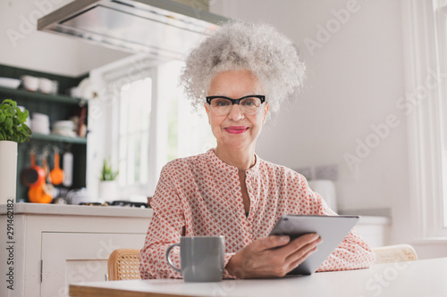Portrait of senior adult female looking at digital tablet at home photo