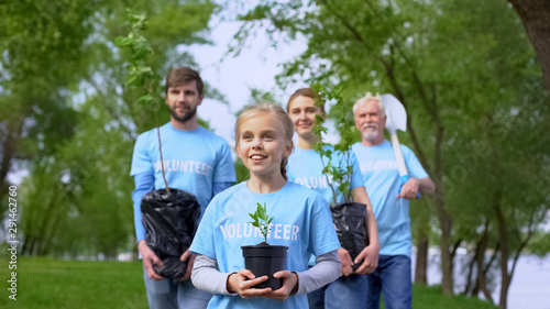 Inspired volunteer child with tree seeding helping family to care about nature