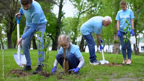 Fotografie Family environmental volunteers planting trees smiling each other, reforestation