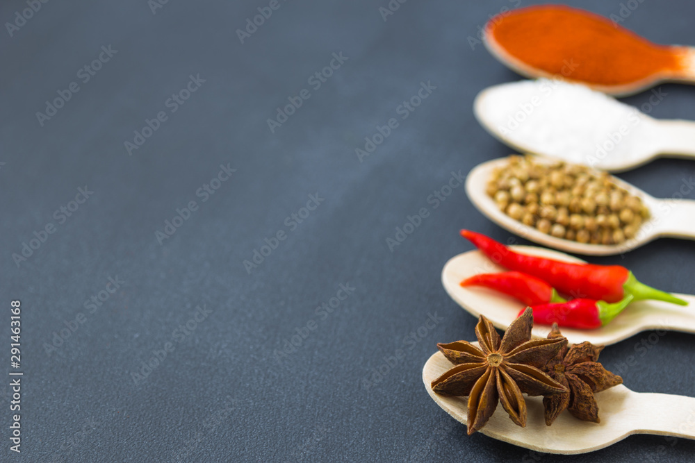 composition of assorted spices in wooden spoons on a dark background. star anise in the front. close up composition of assorted spices in wooden spoons on a dark background. star anise in the front. close up