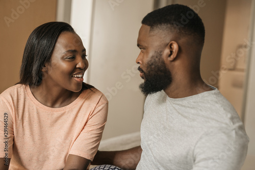 Smiling young African American couple talking together on their bed