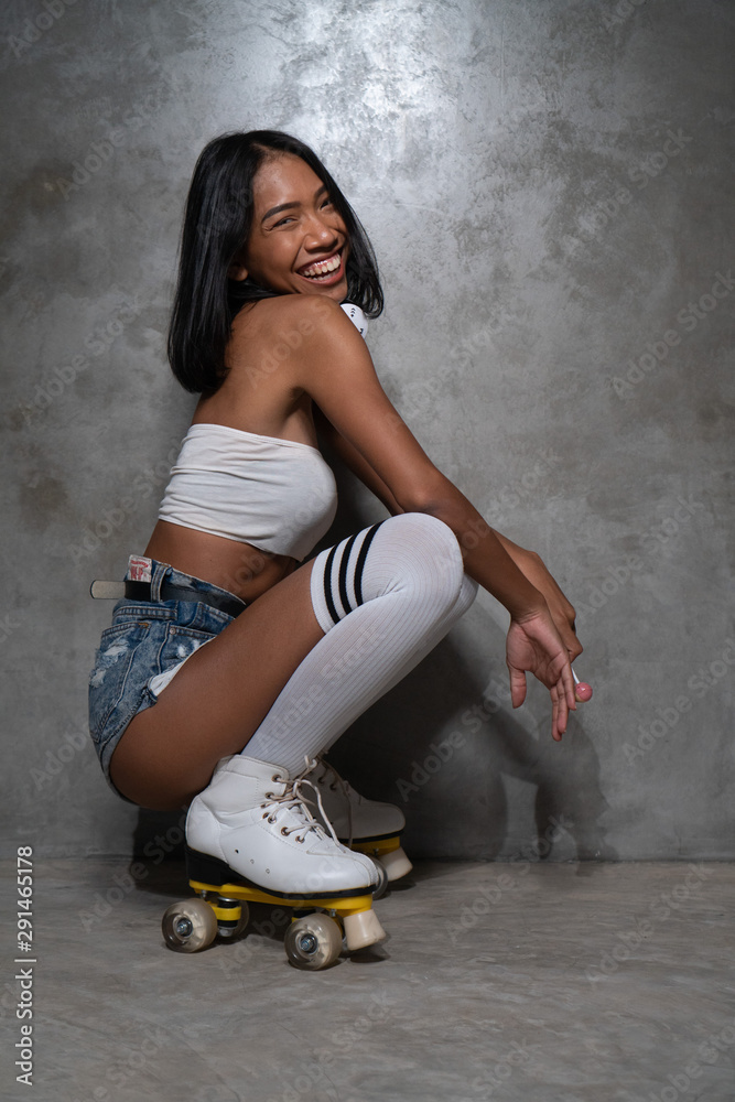 Young beautiful Asian girl in retro quads roller skates posing in studio  over concrete wall background Photos | Adobe Stock