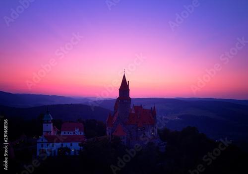 Aerial view on a silhouette of romantic fairytale castle in picturesque highland landscape, against pink and violet evening sky. Castle Bouzov with many towers, Moravia landscape, Czech republic. © Martin Mecnarowski