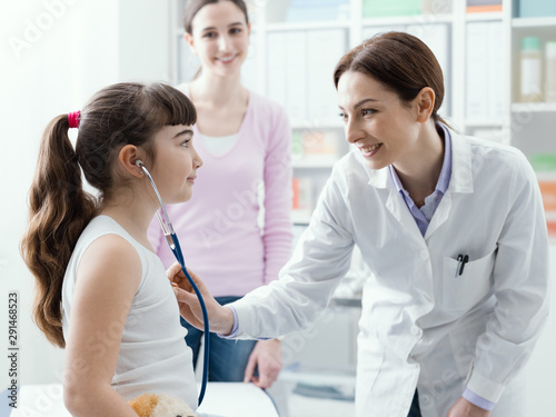 Doctor examining a cute smiling girl with a stethoscope