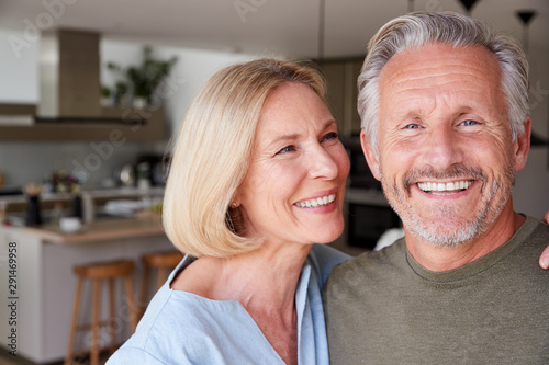 Portrait Of Smiling Senior Couple Standing At Home In Kitchen Together