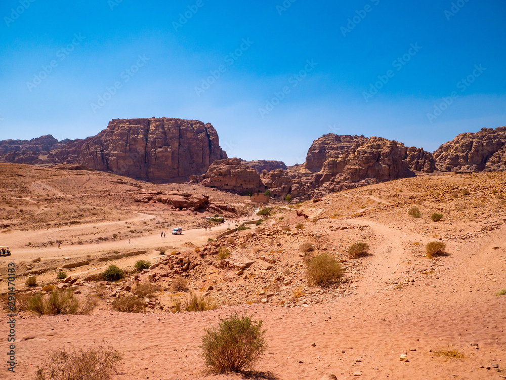 View of the valley of the historic site of Petra, Jordan, orange desert full of temples and a roman amphitheatre, seen from aerial perspective from a sandstone mountain View of the valley of the historic site of Petra, Jordan, orange desert full of temples and a roman amphitheatre, seen from aerial perspective from a sandstone mountain