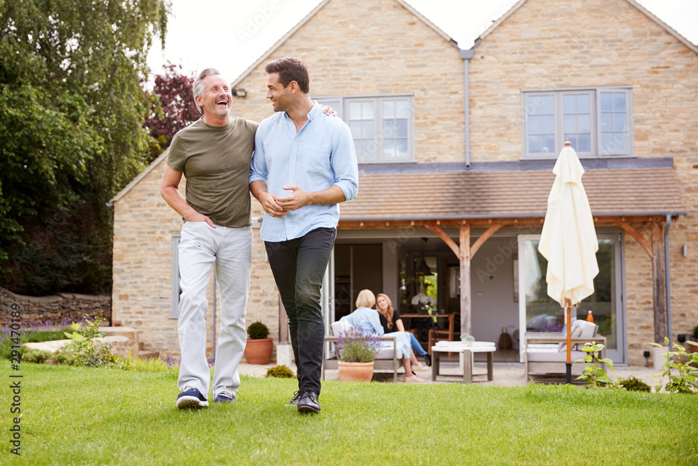Senior Father And Adult Son Walking And Talking In Garden Together Senior Father And Adult Son Walking And Talking In Garden Together