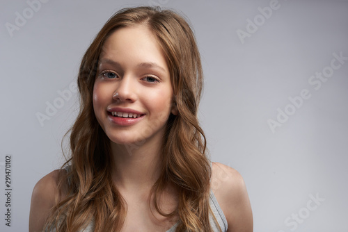 Joyful teen girl standing against gray-white background