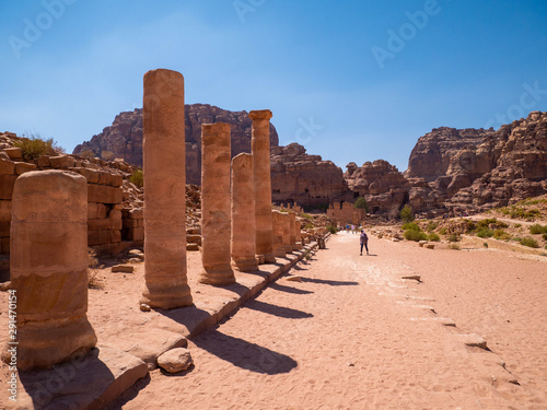 Sandstone clumns at the side of a desert road leading to a mountain full of temples carved into sandstone, historic monument, ruin in the desert of the historic site of Petra, Jordan
