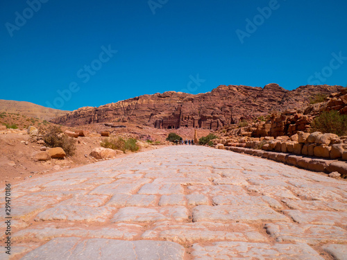 Cobblestone street leading to a mountain full of temples carved into sandstone, historic monument, ruin in the desert of the historic site of Petra, Jordan