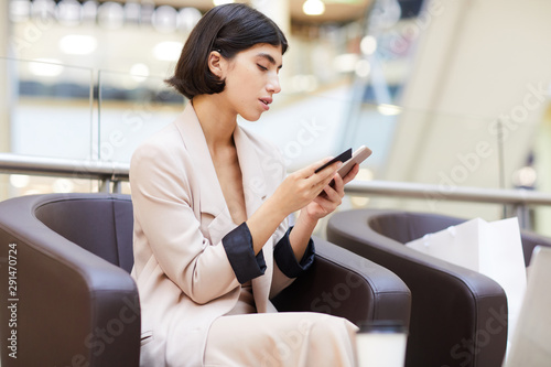 Side view portrait of elegant young woman holding credit card and smartphone while enjoying e-shopping, copy space Free Download Side view portrait of elegant young woman holding credit card and smartphone while enjoying e-shopping, copy space - GFXLoad