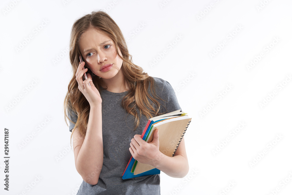 Upset teen girl with books talking on cellphone Upset teen girl with books talking on cellphone