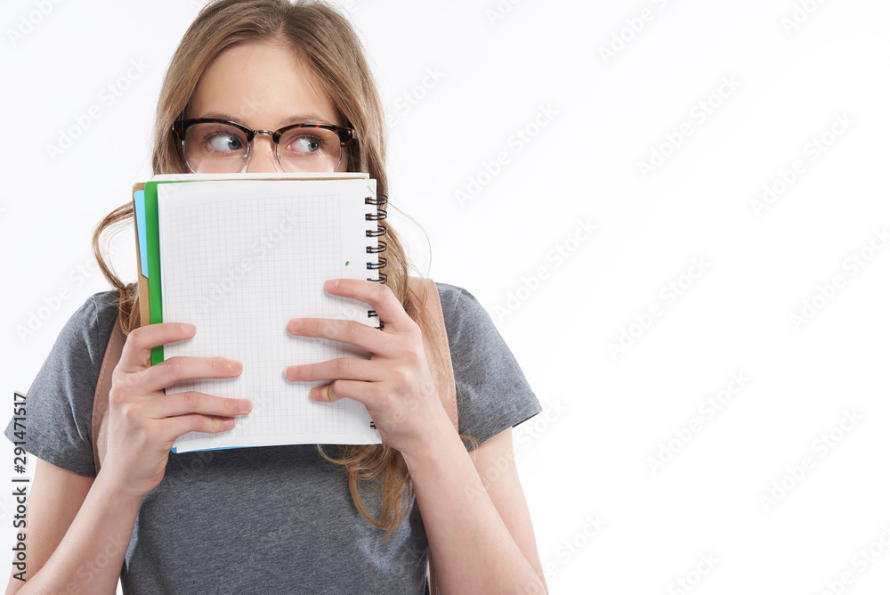Cute teen girl in glasses covering face with spiral notebook Cute teen girl in glasses covering face with spiral notebook