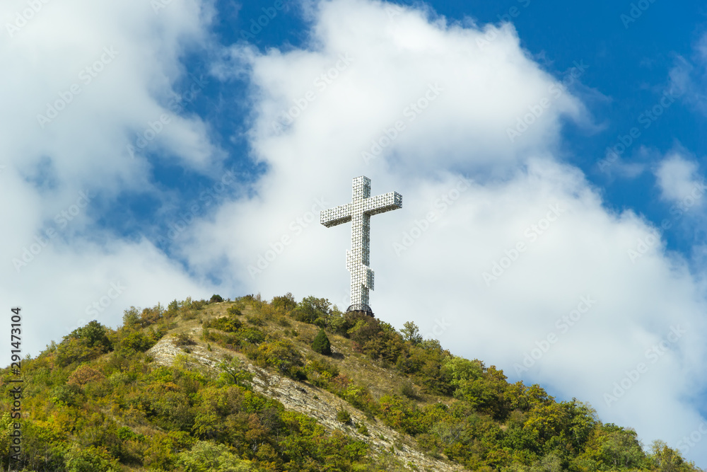 Popular sight of the Gelendzhik resort city. Worship cross on hill of Caucasian mountain against blue cloudy sky background.